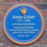 Blue commemorative plaque with a rainbow border honoring Anne Lister (1791–1840), identified as a lesbian diarist. The text notes her union with Ann Walker in 1834 and location in Halifax.